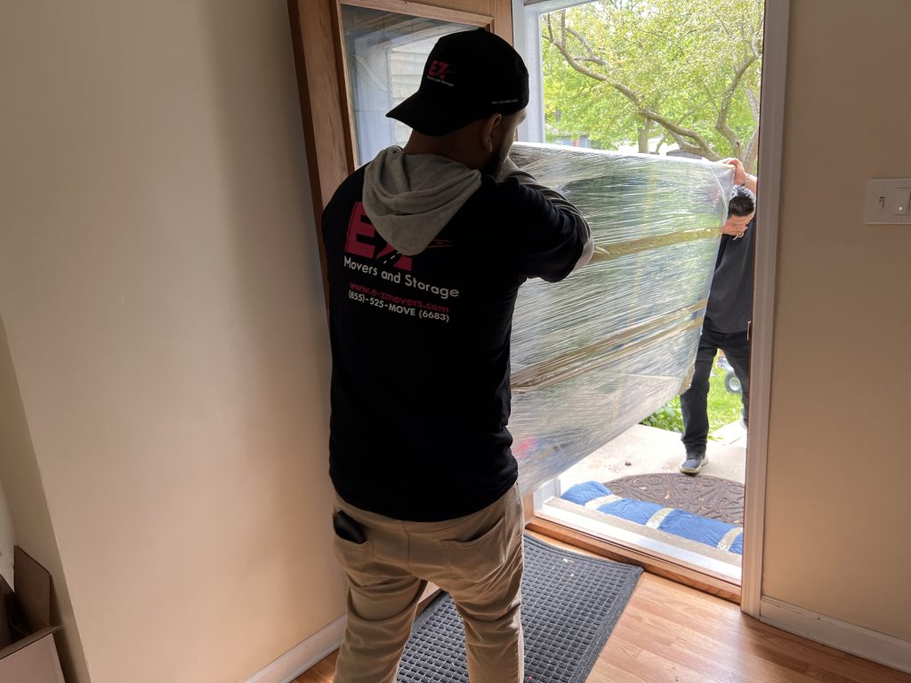 Moving crew carrying a TV and loading onto truck.